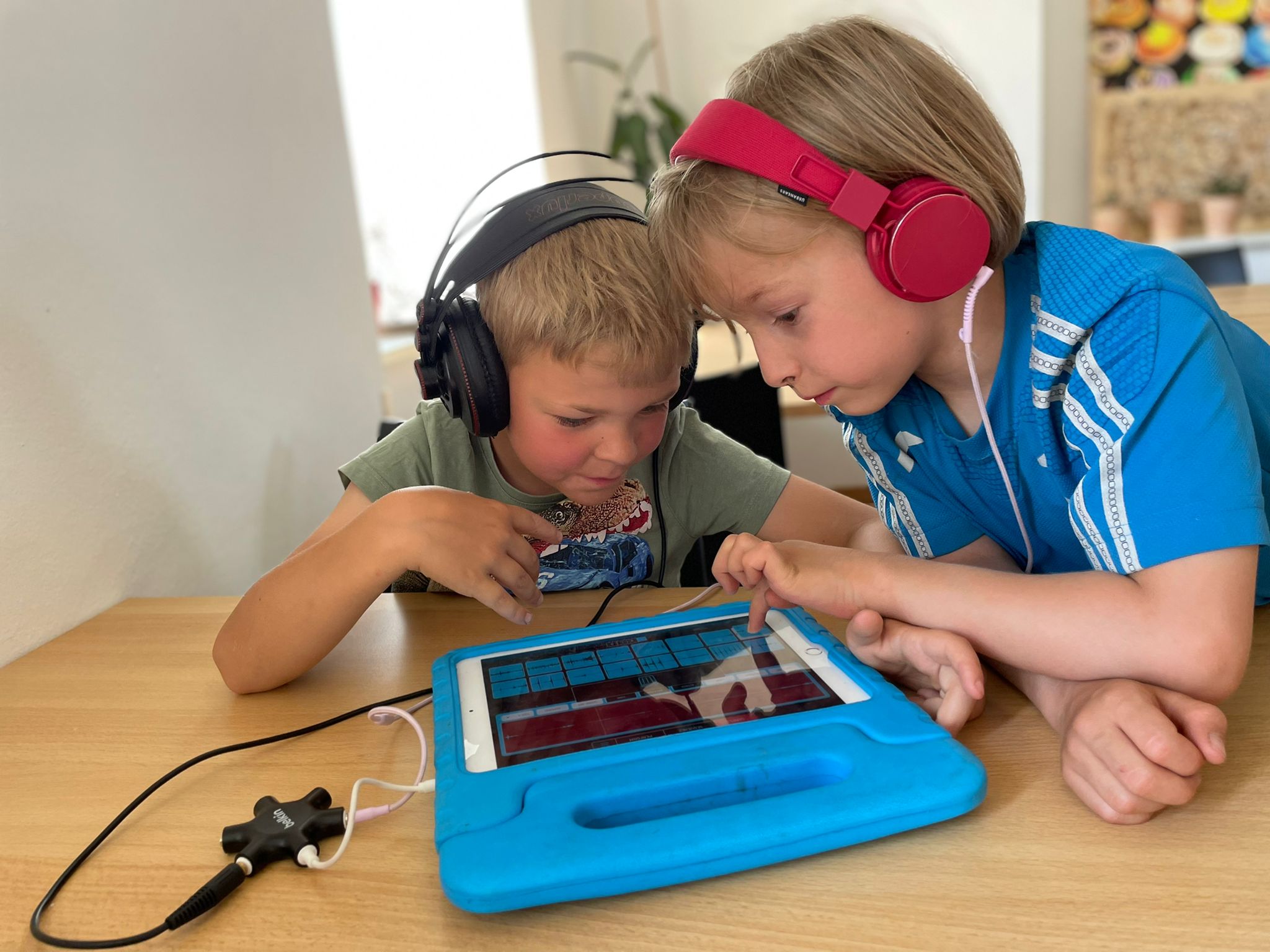 Musikcamp im Juni 2022 auf dem KJB Nickern | Zwei blonde sechs Jahre alte Jungs mit Kopfhörern über ein Tablet gebeugt. Sie machen Musik mittels Musikapps.